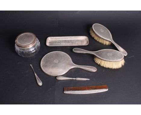 An engine turned silver backed dressing table set engraved initials "LKL", comprising two hairbrushes, a mirror, a powder bow