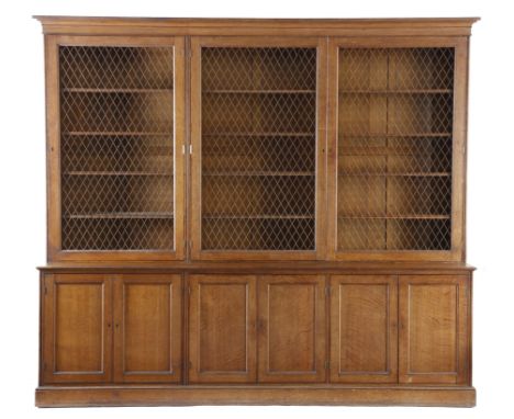 A late Victorian oak bookcase, the detachable moulded cornice above three brass lattice grille doors, each enclosing four adj