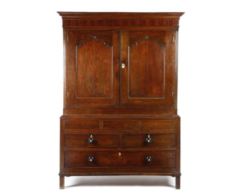 A George III Welsh oak press cupboard, the mahogany frieze above a pair of arc d'arbelète panelled doors, enclosing a vacant 