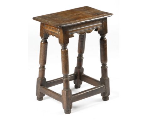 A mid-17th century oak joint stool, the seat with a moulded edge, above moulded bicuspid rails, on slender turned sausage leg