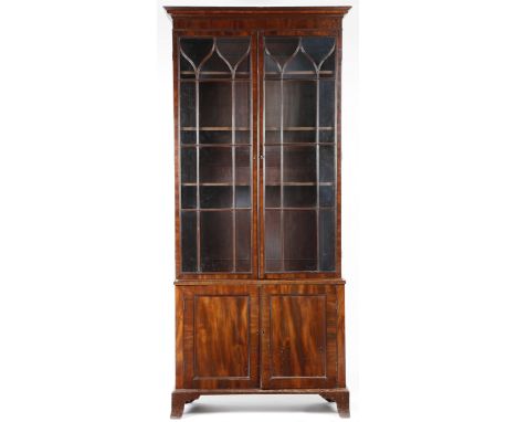 A mahogany bookcase cabinet in Regency style, with a pair of lancet astragal glazed doors, enclosing three adjustable shelves