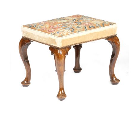 A George II walnut stool, the stuffed-over needlework seat worked with gros and petit point with scrolling leaves and flowers