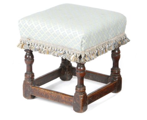 A Charles II upholstered oak stool, the seat with a later fabric cover, on turned legs united by peripheral stretchers, 42.5c