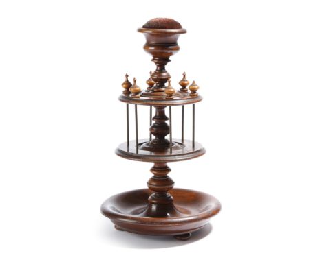 λ An early 19th century rosewood seamstress' bobbin stand, the top with a pin cushion, above six turned finials and a dished 