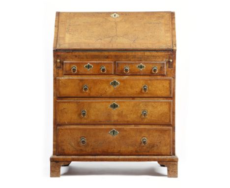 A George II walnut bureau, with cross and feather banding and burr panels, the hinged fall revealing an arrangement of pigeon