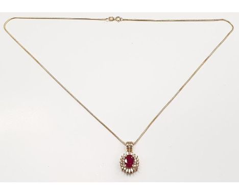 14ct yellow gold ruby and diamond pendant necklace. The central ruby of 1ct surrounded by diamonds. 