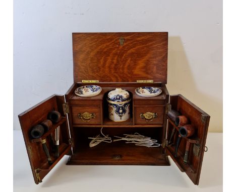 An oak carved pipe smokers cabinet with pipes.