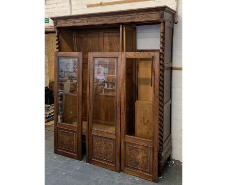 A French oak wardrobe, the blind carved frieze over three glazed and carved doors (one with glass missing); opening to adjust