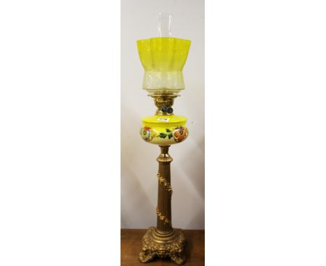 A large antique metal column oil lamp with yellow fount and etched yellow glass shade, overall H. 86cm.