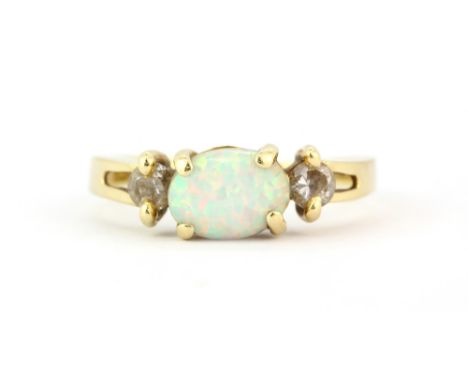 A 14ct yellow gold (stamped 14k) ring set with a cabochon oval cut opal and stone set shoulders, (possibly synthetic opal), (