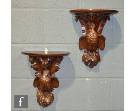 A pair of late 19th Century Black Forest carved oak wall bracket shelves, each with a demi-lune platform over acanthus leaf b