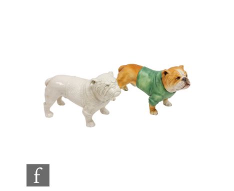 Two model bulldogs, the first in brown wearing a green jumper, the second in white with a ribbed jumper, both unmarked, possi