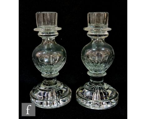 A pair of early 19th Century clear crystal glass candlesticks with a fluted sconce above a hollow blown knop with basal fluti