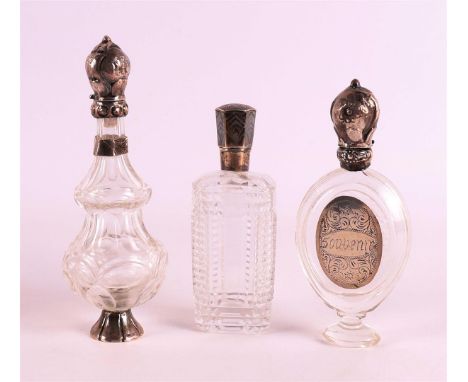 A clear crystal odeur flask with silver flip lid and frame, 19th C., including stopper, h11 cm. Hereby two others with silver