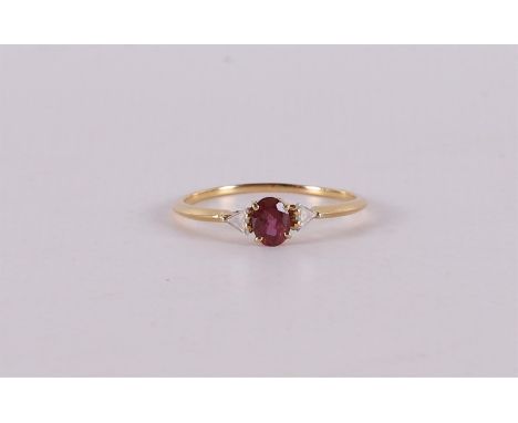 An 18 carat 750/1000 gold ring with an oval faceted ruby flanked by 2 triangle cut diamonds. Ring size 19mm.