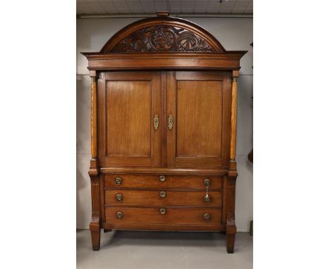 A two-door cabinet, Northern Netherlands, early 19th century. Oak, curved profiled hood with carving in the motif of a vase o