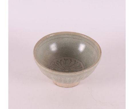 A celadon porcelain bowl on a stand ring, China 15th century. In the center decoration of flower, h 5 x Ø 9.5 cm.