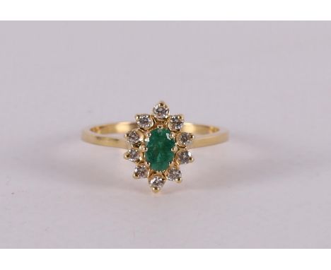 An 18 carat 750/1000 gold ring with an oval faceted emerald and an entourage of 16 diamonds H-VS. Ring size 18.5 mm.