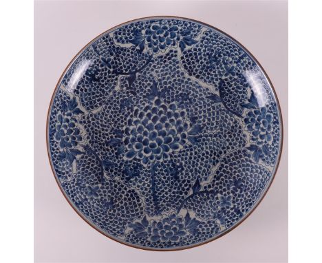 A blue and white porcelain dish, China, Kangxi, early 18th century. Blue underglaze floral decor with café au lait edge, Ø 41