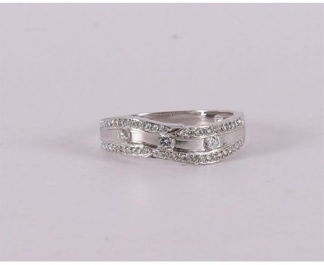 An 18 kt 750/1000 white gold band ring with 3 brilliants of 0.05 ct each, flanked by 54 smaller ones. Ring size 17.25 mm.