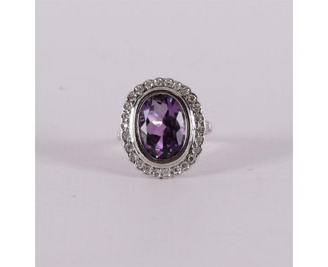 An 18 carat 750/1000 gold ring with an oval faceted amethyst and an entourage of 28 octagonal cut diamonds. Ring size 16.25 m