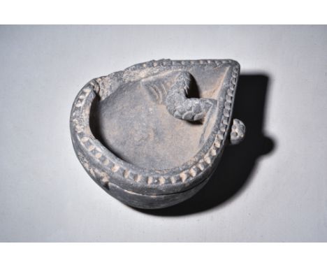 Ca. AD 200-300.A schist stone teardrop-shaped oil lamp with a flat base, serrated rim, two bud-shaped protrusions to the tipp