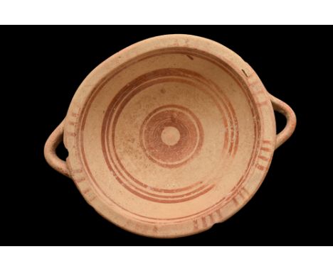 Ca. 700-600 BC.A pottery dish of a shallow form with two horizontally oriented handles positioned on opposite sides. The rim 