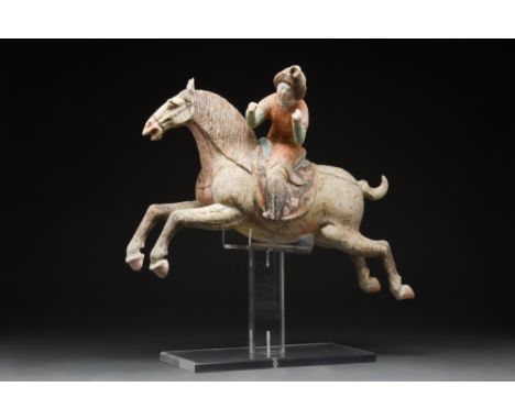Tang Dynasty, Ca. AD 618-907.A Tang dynasty terracotta female polo player, seen riding a hollow-moulded horse. The rider's fa