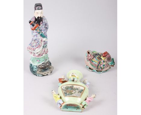 A Chinese polychrome decorated figure of a man holding a sword, a green glazed wall pocket with relief decorated figures, and