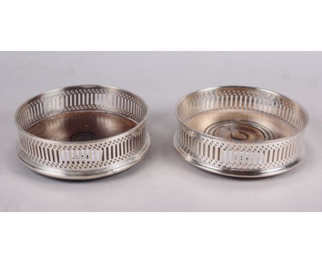 A modern silver wine bottle coaster with pierced sides, on turned wooden base, and an almost matching silver plated coaster 