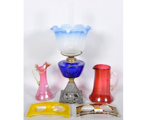 An oil lamp, two cranberry glass jugs and two glass sanitiser dispenser stands