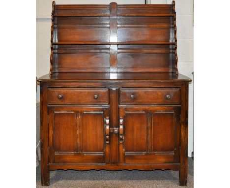 A 20th Century Ercol colonial dresser having plate rack top above cupboard. Measures; 150cm x 123cm x 46cm.