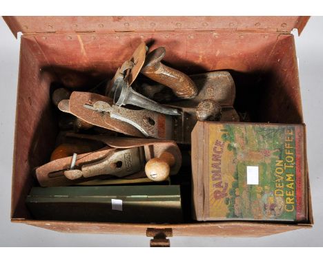 A vintage safe box tin trunk containing a collection of planes and other tools.