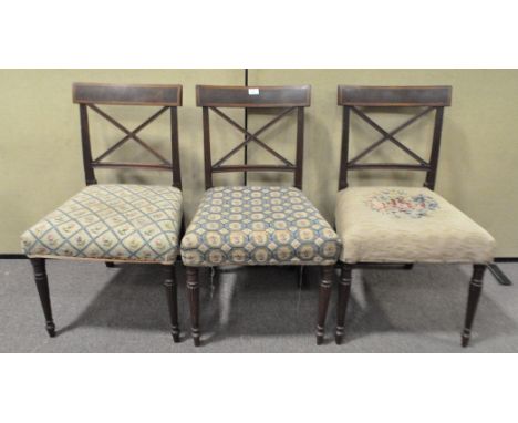 A set of three 19th century mahogany dining chairs with tapestry upholstered overstuffed seats, raised on turned reeded legs.