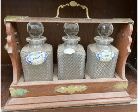 A three decanter tantalus with ceramic wine labels