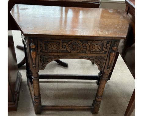 A 20th century oak side table with a carved frieze drawer on ring turned legs
