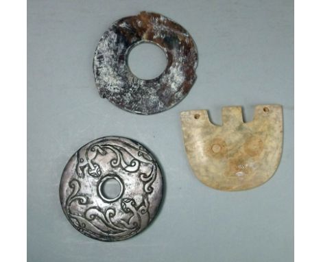 A Chinese jade disc, Bi, one other stone disc and a pendant: the first carved to each side with chilong, 9 cm diameter; the s