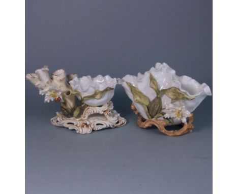 Two Moore Bros. porcelain comports: one modelled with a cherub astride a dolphin supporting a bowl with lotus leaves and bloo