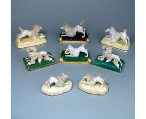 A group of eight Staffordshire porcelain figures of poodles: comprising a matched pair of a bitch and three pups on a green c