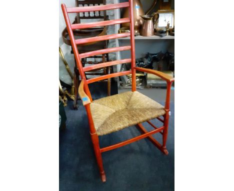 An early 20th century red painted ladder back rocking chair with rush seatLocation: 