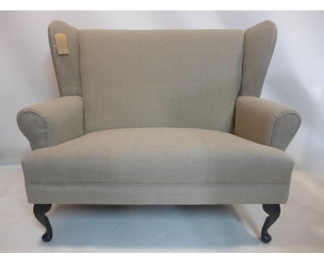 A two seater wingback sofa, raised on cabriole feet, H.107 W.128 D.68cm 