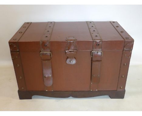 A brown leather trunk, with double strap detailing to front and side handles on wooden base, 48 x 79 x 43cm 
