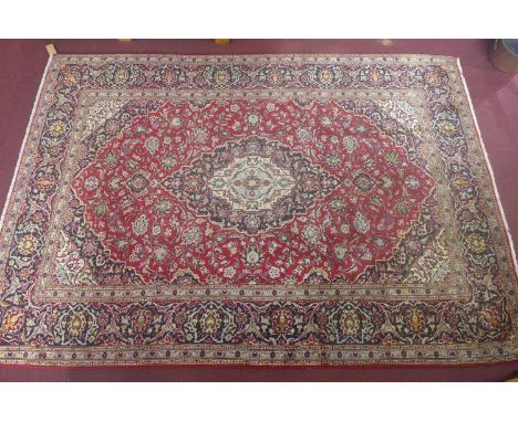 A Central Persian Kashan carpet, central double pendent medallion with repeating petal motifs and spandrels on a rouge field,