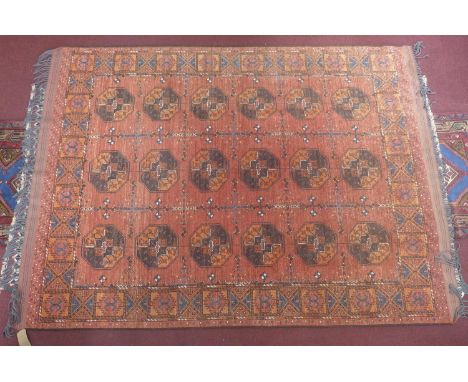 A Pakistani Turkoman hand-made woolen carpet, elephant pad motifs on a rouge field, within geometric border, 273 x 198cm 