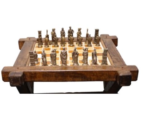 A stained pine chess table, the rectangular Glastonbury type hinged top inset with brown and cream ceramic tiles on X shaped 