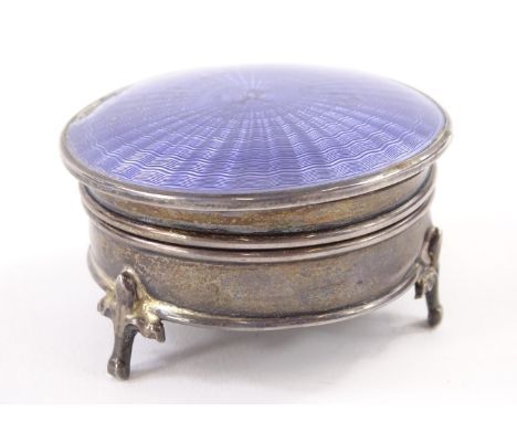 A George V silver trinket box, the hinged lid with purple guilloche enamel, in three feet, (enamel AF) etc., 6cm diameter.