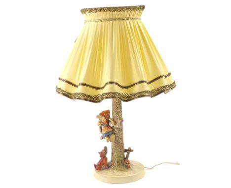 A Goebel Hummell lamp base, modelled in the form of a girl, seated in a tree with a dog, 40cm H overall.