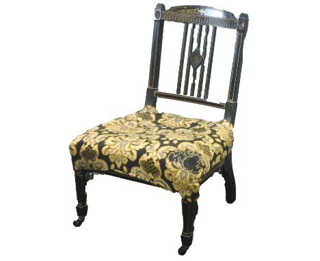 A Victorian ebonised nursing chair,  with simulated ivory inlay, in near classical style, on square tapering legs with cerami