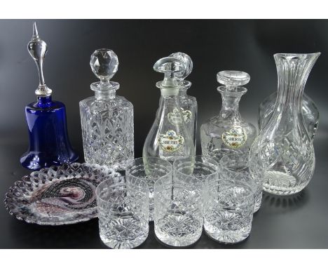 Various square section and circular decanters and stoppers, some with ceramic labels, a blue glass bell, a Sowerby type ribbo