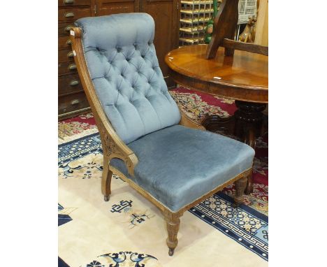 A Late-Victorian oak-framed upholstered button-back salon chair on reeded front legs.